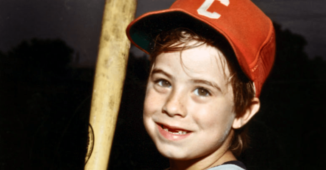 Adam Walsh dressed in baseball gear and holding a baseball bat